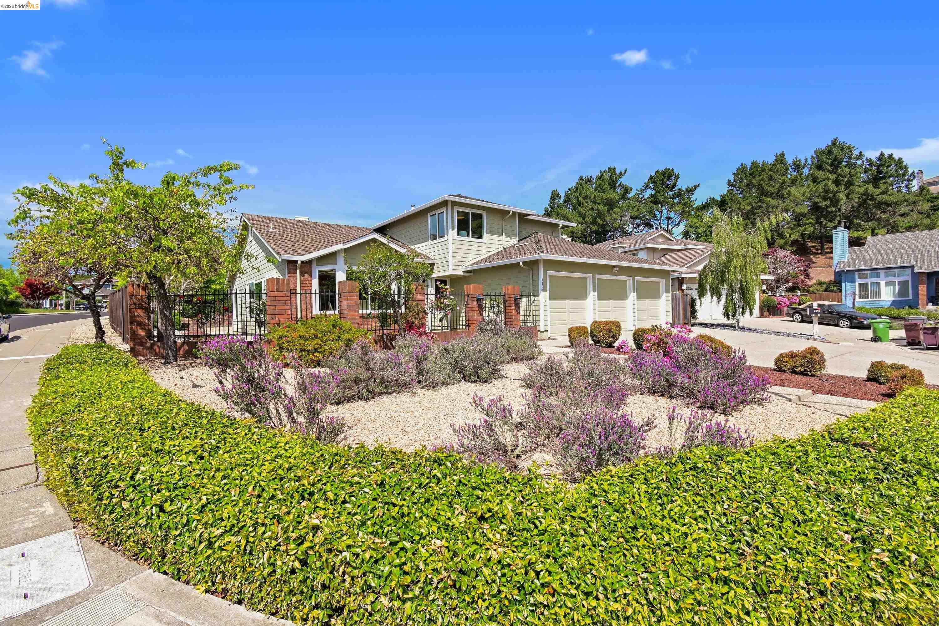 Streetside view of 4303 Chamberlin Ct from the Chamberlin Court cul-de-sac, sage clapboard facade set behind a landscape island of blooming lavender and mature pines