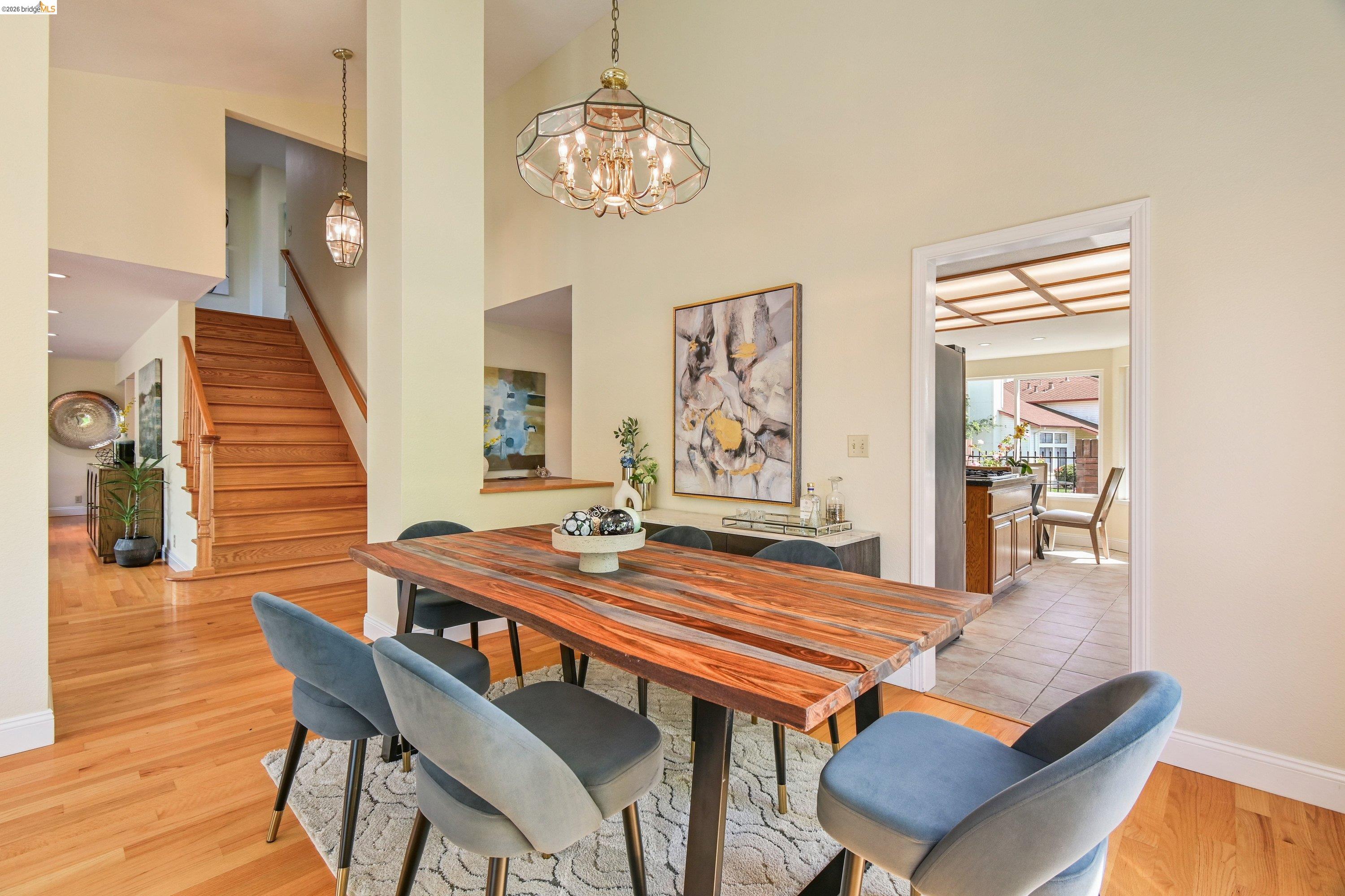 Formal dining room beneath a hammered-bronze chandelier, hardwood floors, an open archway leading to the kitchen