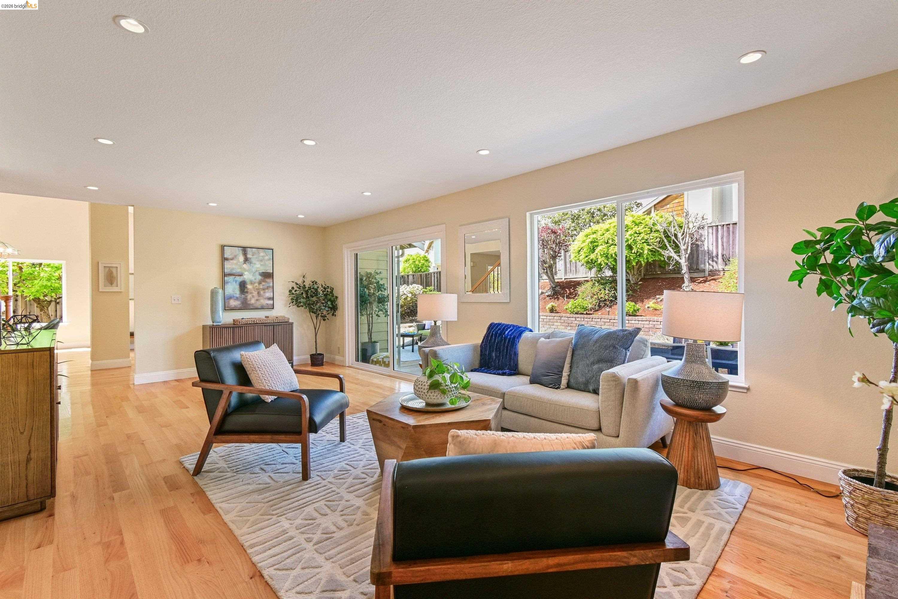 Family room with a floor-to-ceiling brick wood-burning fireplace, oak floors, and wide windows opening to the back garden