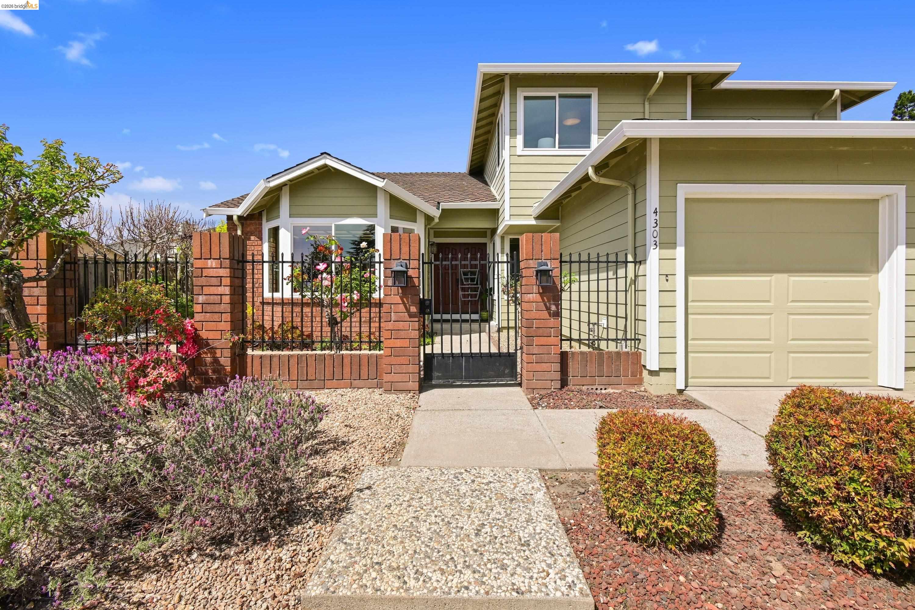 Front entry of 4303 Chamberlin Ct, a two-story Ridgemont contemporary in sage clapboard with a brick-piered courtyard, iron gate, bay window, and the address 4303 on the garage